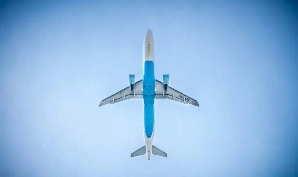 Passenger airplane flying overhead against a clear blue sky, viewed from below