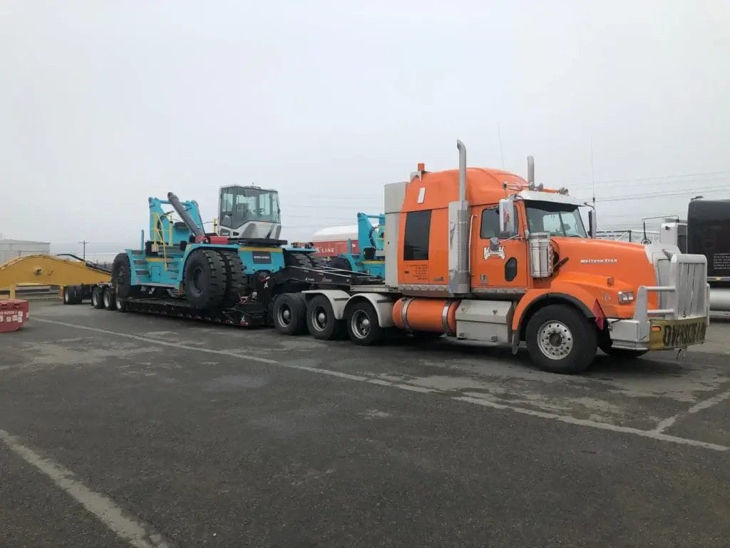Oversize flatbed truck hauling heavy construction equipment